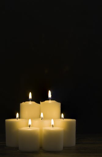 A closeup shot of a group of seven burning candles with black background