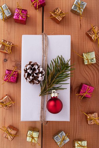 The flat lay of a white decorated gift box and Christmas decorations in the wooden background