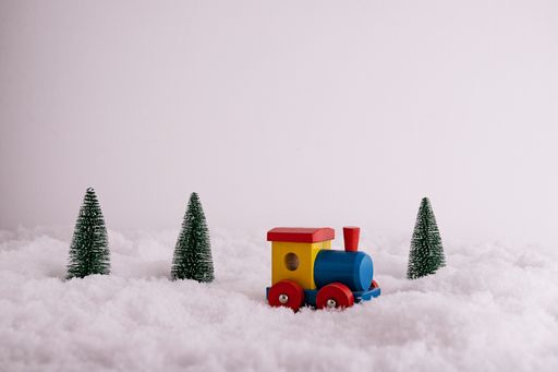 A closeup of a toy train and fir-trees in the snow