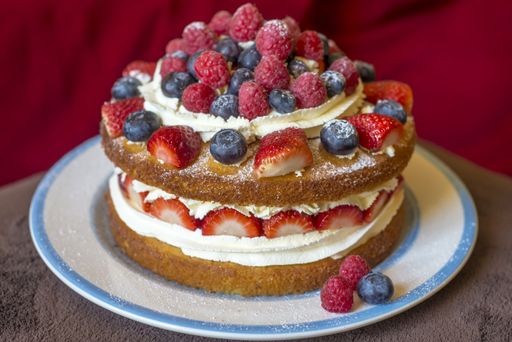 A closeup shot of a delicious creamy pie with strawberry, raspberry and blueberry garnish
