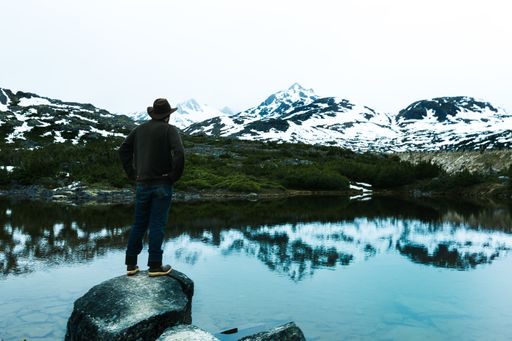 A man standing on the stone near the lake in Alaska