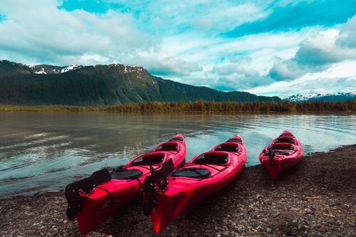 Red kayaks parked on the lakeshore with the mountains in the background