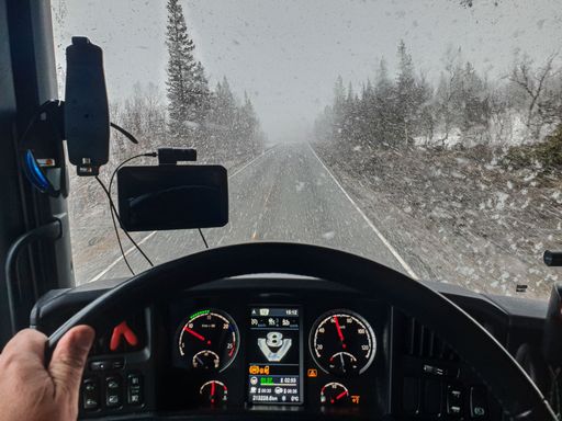 View from inside a truck driving in heavy snow.