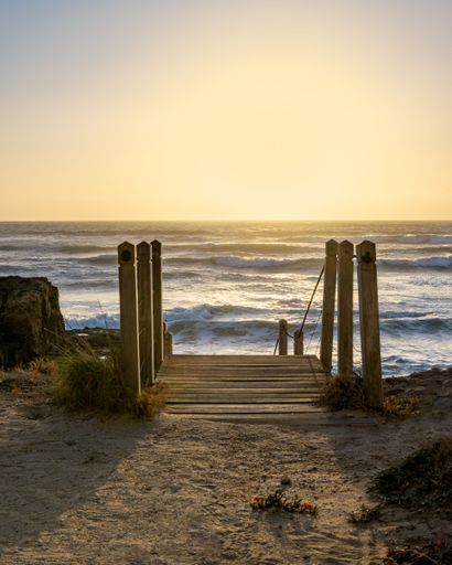 A vertical shot above a wooden stairway to the sea during golden hour in Italy