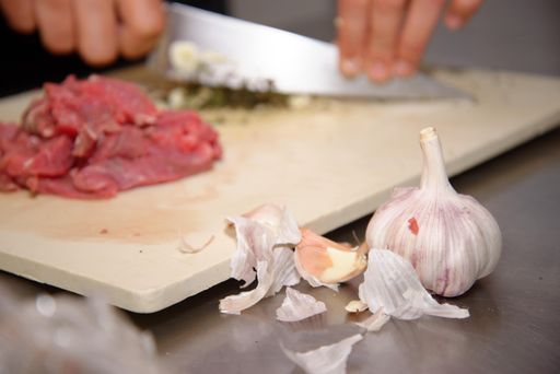 A closeup of garlic pieces on background of hands cutting ingredients
