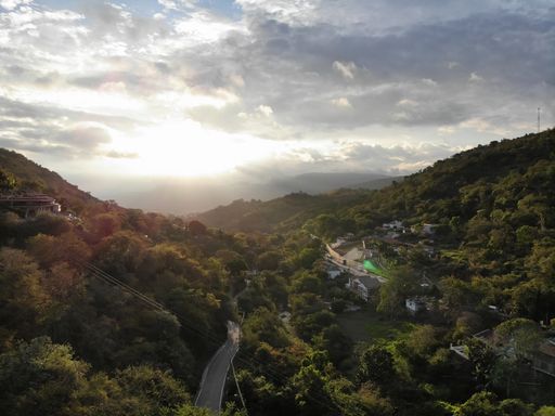 Highway in the Middle of Trees and Houses, Buildings Surrounded by the Green Mountains at Sunset in San Gil / Colombia