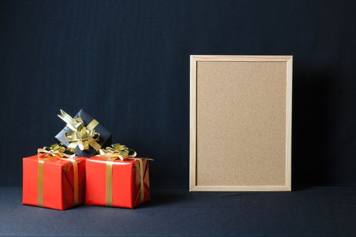 A corkboard and Christmas gift boxes with copy space isolated on a dark background