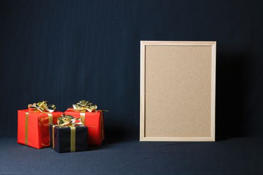 A corkboard and Christmas gift boxes with copy space isolated on a dark background