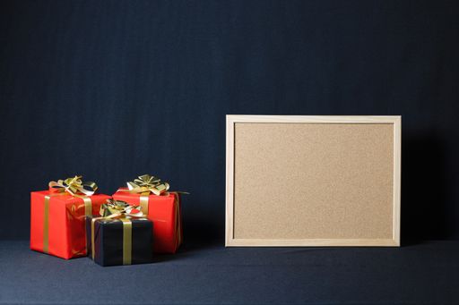 A corkboard and Christmas gift boxes with copy space isolated on a dark background