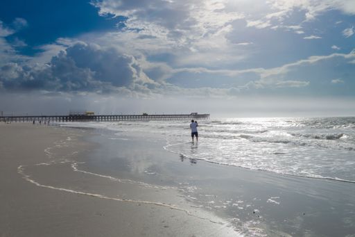 A back view of a father holding his baby and standing in the sea water
