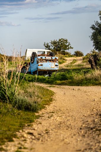 A vertical shot of an old car in a junkyard near Limassol city
