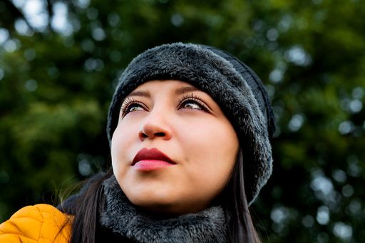 A cool and pretty Caucasian woman wearing a bonnet and a winter coat on a blurred background
