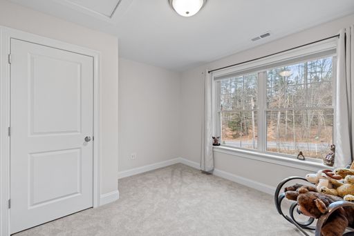 A white room with big windows and a rocking chair full of stuffed animals