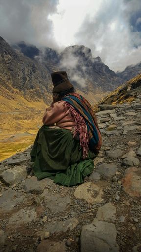 A vertical shot of a native woman sitting on a stony road