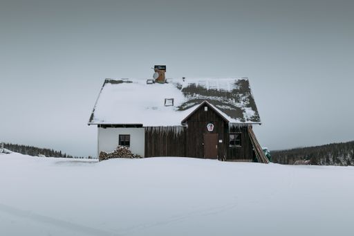 A landscape of a wooden house covered with snow during the winter