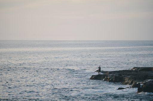 A beautiful shot of a person standing at a rocky beach by the sea