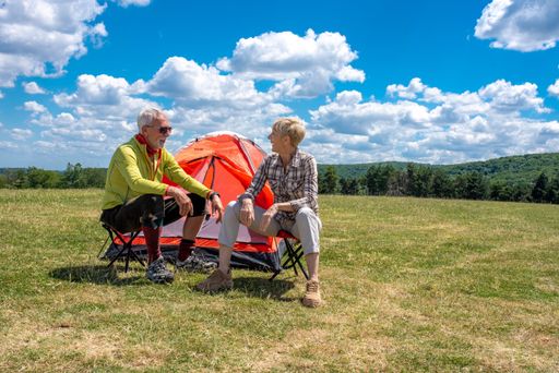 A senior couple having a rest in the field with a tent in the background