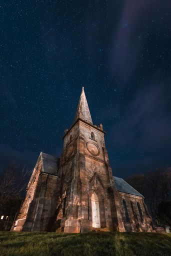 A vertical shot of a small church under the starry sky with the Milkyway in Tasmania, Australia
