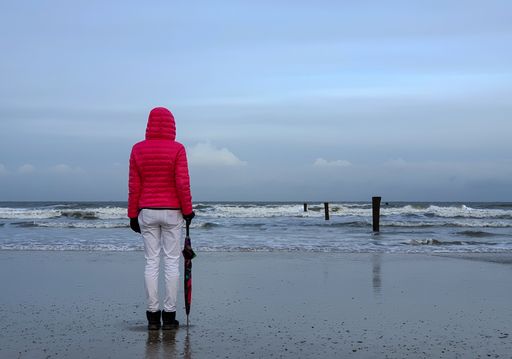 People walking by the sea under a cloudy sky