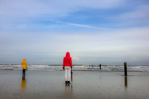 People walking by the sea under a cloudy sky