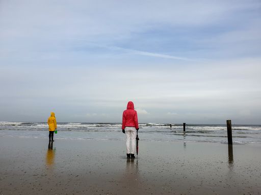 People walking by the sea under a cloudy sky