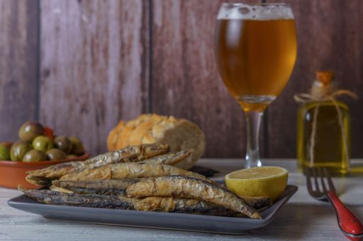boquerones fritos rebozados . fried anchovies in batter typical of southern spain with olives, bread and beer