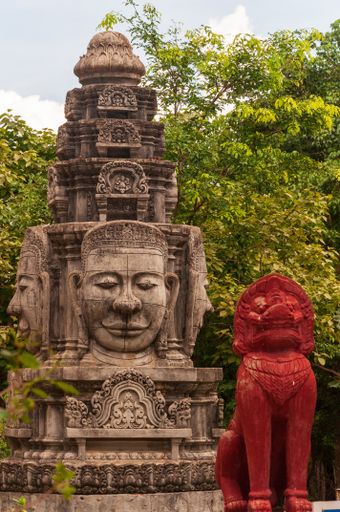 A vertical shot of an ancient historic statue surrounded by a green scenery in Phnom Penh in Cambodia