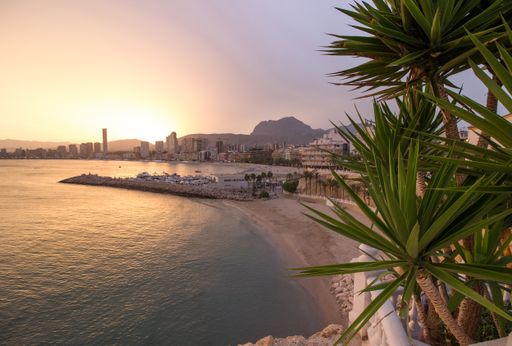An aerial shot of a beach next a town during sunset