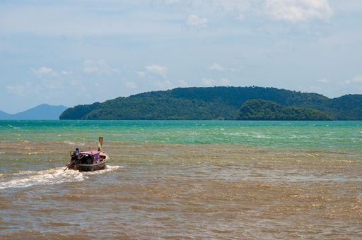 A boat riding in the ocean surrounded by a green scenery in Ao Nang Krabi, Thailand, Asia