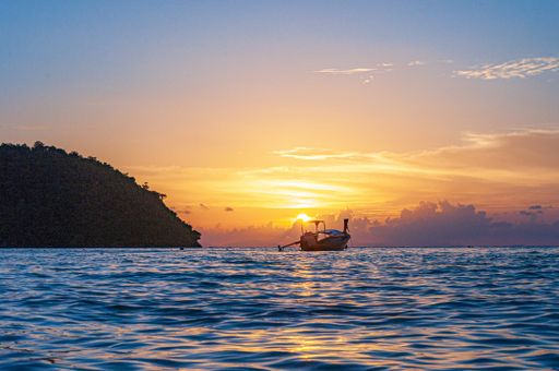 A ship sailing in the ocean during a breathtaking sunset in Koh Phi Phi Island, Thailand
