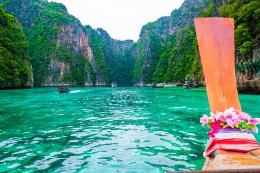 A low angle shot of a rock formation interacting with the clean ocean water in Koh Phi Phi Island, Thailand