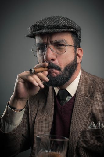 A Hispanic businessman smoking his cigar isolated on gray background