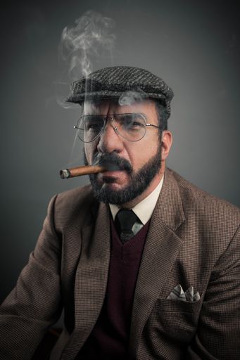 A Hispanic businessman smoking his cigar isolated on gray background
