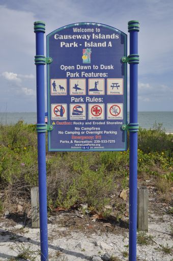 A vertical shot of a sign in front of a beach in Sanibel Island, Miami, USA