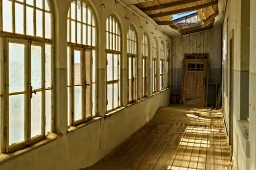 An abandoned hallway in an ancient building with a wooden floor and a broken roof