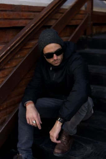 A white caucasian male with glasses and hoodies sitting on the stairs
