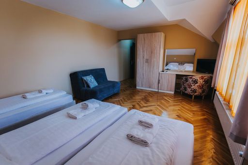 A triple room under the lights with a small table and curtains in a hotel