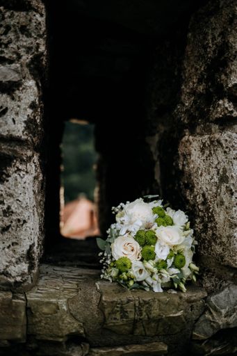 A vertical selective focus shot of a bouquet of flowers in an old brick wall