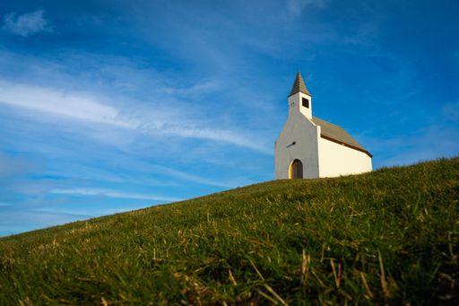 A low angle shot of a small church on a rural green hill in the Netherlands