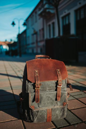 A vertical shot of a leather backpack on the sidewalk