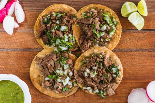 The flat lay of appetizing tacos, lemon, sauce, and radish on the table