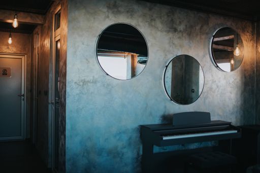 A room with a synthesizer and three round mirrors hanging on the wall