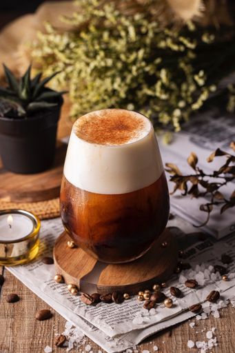 A vertical selective focus closeup of a glass of fresh coffee
