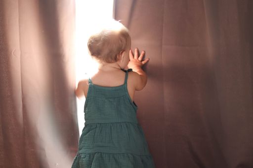 A 10 month old Caucasian baby girl playing in her room wearing a blue-green dress