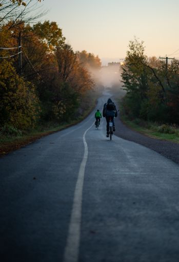 A vertical shot of cyclists riding on a countryside road on a morning