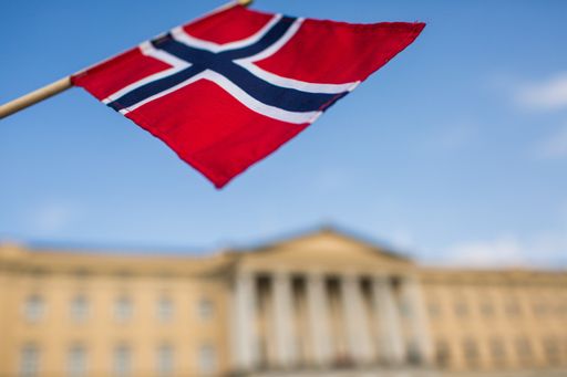 The flag of Norway with the Royal Palace in the background