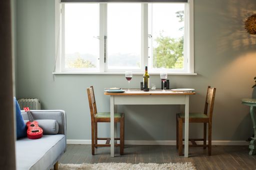 A table for two people near the window with wine glasses and a wine bottle on it