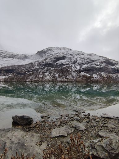 A scenic vertical shot of a beautiful snowy mountains reflecting on a lake in Norway