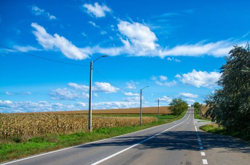 A beautiful asphalt road near a big agricultural field