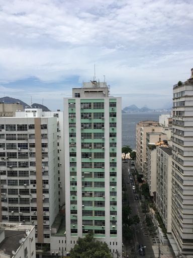 A scenery of skyscrapers under a cloudy sky with the beach in Rio De Janeiro on the background